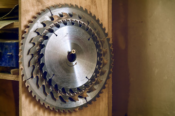 Many metal circular saw blades different sizes on a wooden background in workshop