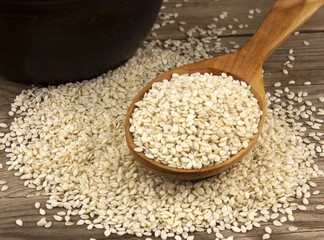Sesame in a bowl on wooden background with a wooden spoon