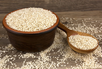 Sesame in a bowl on wooden background with a wooden spoon