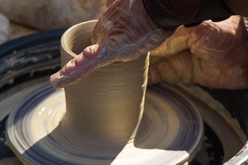 adult hand fed baby's hands to work with a potter's wheel