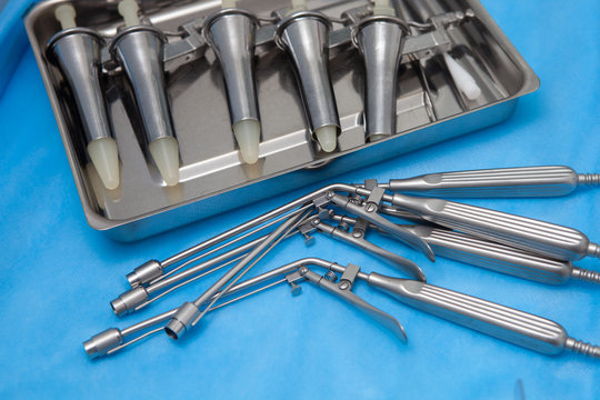 Anoscopes and ligators for the diagnosis and treatment of hemorrhoids made of stainless steel on a blue medical tablecloth