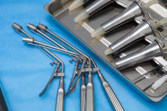 Anoscopes and ligators for the diagnosis and treatment of hemorrhoids made of stainless steel on a blue medical tablecloth