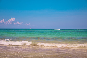 View of tropical beach. Tourists ride parasailing boat with parachute. Sailing yacht sails on waves. Turquoise water of the Caribbean Sea. Riviera Maya Mexico.