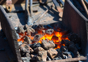 blacksmith furnace with burning coals, tools, and glowing hot metal workpieces