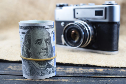 earnings in photography, a camera and money (dollars) are on the table