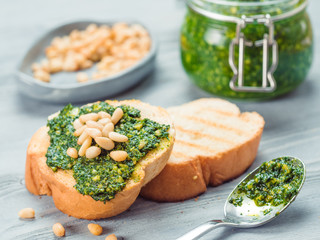 Close up view of baguette bread with fresh basil pesto sauce on gray wooden table