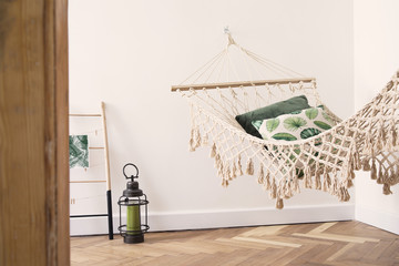 Modern and stylish bedroom with natural string hammock. Bright and sunny bedroom with brown wooden...