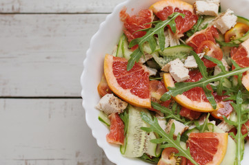 Healthy summer salad: red grapefruit, fresh arugula, cherry tomatoes, cucumber and baked chicken breast served in white bowl. Balanced meal concept