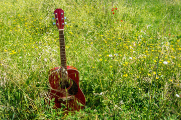 Obraz premium Close-up of acoustic guitar lying on a meadow and grass, vintage style with copy space