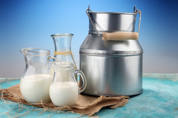 A jug of milk and glass of milk on a wooden table