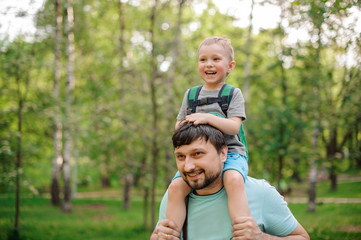 Naklejka na ściany i meble Happy bearded father carrying his son on his shoulders
