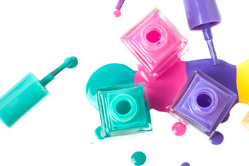 group of three colorful nail polish bottles on spilled paint