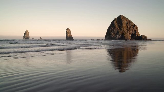 Haystack Rock and the Needles, Cannon Beach 4K. UHD. Sunrise at Haystack Rock and the Needles in Cannon Beach, Oregon as the surf washes up onto the beach. United States.
