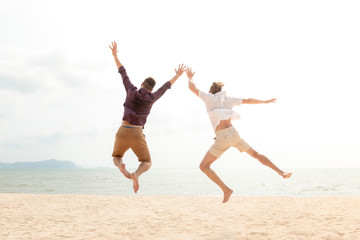 Fototapeta na wymiar Young energetic happy tourist men jumping at the beach