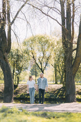 Naklejka premium Beautiful young couple in the Park on a Sunny day, loving and happy. Walk and laugh with the dog. Pre-wedding shooting in nature. Casual style in clothing and European in processing