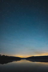 Obraz na płótnie Canvas Blue dark night sky with many stars above field of trees.