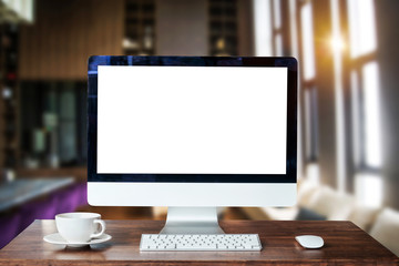 Workspace with computer Monitor, Keyboard,blank screen coffee cup on a table in bright office room interior.