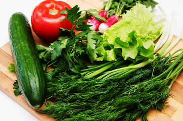 fresh vegetables and herbs laid out on a wooden Board