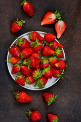 Fresh, juicy strawberries in a plate on a dark rustic background. Proper nutrition. Organic food.