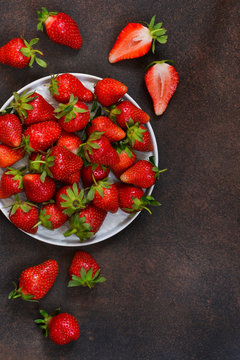 Fresh, juicy strawberries in a plate on a dark rustic background. Proper nutrition. Organic food.