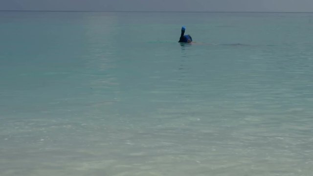 A man swims under the water with a diving mask and shoots video on the phone, taking selfies.