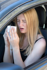 Woman reacts with pollen on hay fever in a car