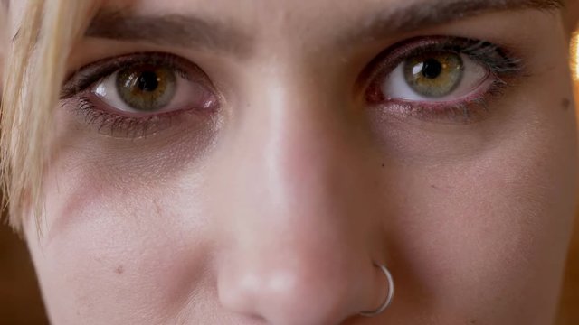 Young attractive hipster girl opens eyes, watching at camera, brick background, closeup