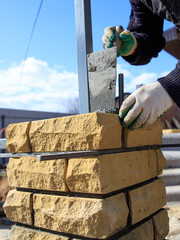 man builds a brick wall at a construction site