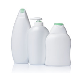 Blank white mockup dispenser and plastic bottles of cosmetic products with green lids
