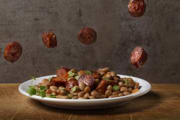 Beans with smoked pork sausages on plate and tomato sauce