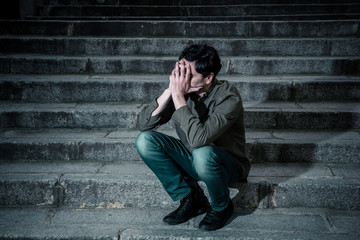 depressed man sitting out side on steps feeling tired and sad.