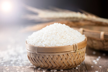 raw rice in a bamboo basket with wheat on wooden background