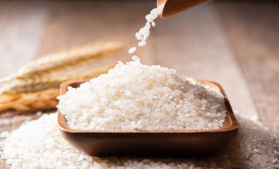 raw rice in a wooden bowl on wooden background