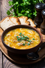 chicken soup with egg noodles in a bowl on wooden background, vertical