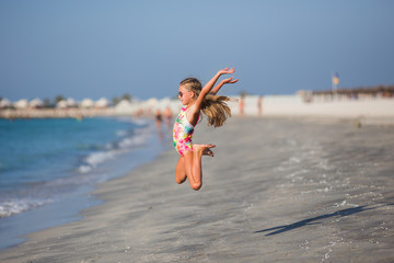 little girl  jumping on the beach on blue sea shore in summer vacation at the day time
