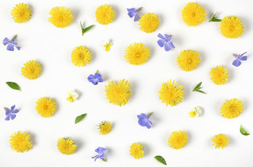 Obraz premium Floral pattern made of yellow dandelion, lilac flowers and leaves isolated on white background. Flat lay. Top view.