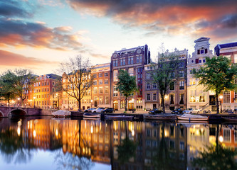 Fototapeta premium Domy nad kanałem amsterdamskim na zachodzie słońca, Holandia