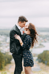 Young stylish couple in the forest, running around the Park and laughing. Modern people on a walk. Beautiful girl with tattoos. Loving young man and girl. mountain Park with pine forest