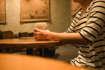 lifestyle background woman holding coffee glass sitting alone in restaurant with copy space. image for food, person, beverage, portrait concept