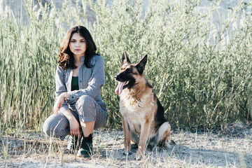 Cute girl playing with her dog against the background of the field