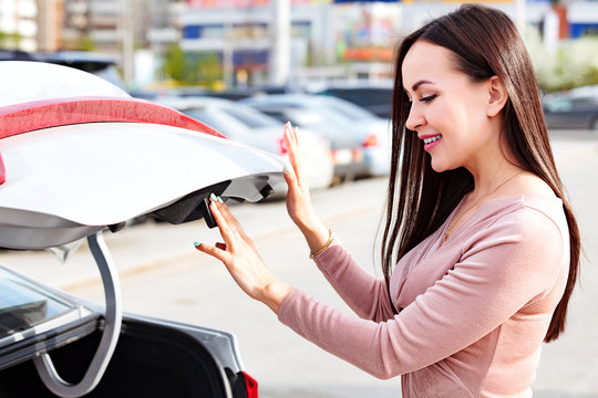 Young Pretty Woman Is Opening The Trunk Of Her Car