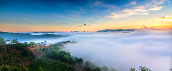 Dawn on plateau in morning with colorful sky, while sun rising from horizon shines down to small village covered with fog shrouded  landscape so beautiful idyllic countryside Dalat plateau, Vietnam