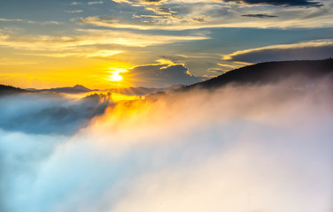 Dawn on plateau in morning with colorful sky, while sun rising from horizon shines down to small village covered with fog shrouded  landscape so beautiful idyllic countryside Dalat plateau, Vietnam