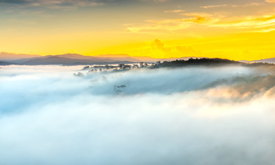 Dawn on plateau in morning with colorful sky, while sun rising from horizon shines down to small village covered with fog shrouded  landscape so beautiful idyllic countryside Dalat plateau, Vietnam