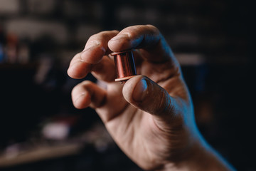 Close-up induction electric coil made of copper wire in hands of worker.