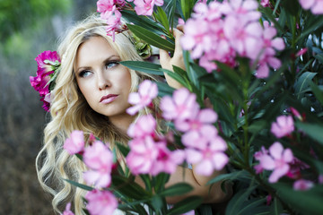 Fototapeta premium Romantic portrait of beautiful young blond woman surrounded by pink flowers