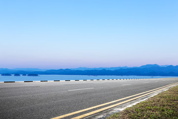 asphalt road and blue sky with white clouds by the lake