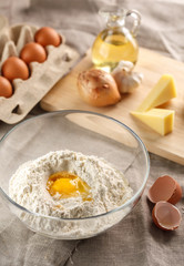 preparation of dough for flat bread. broken egg and flour in a glass bowl. flat bread with onion, cheese and garlic