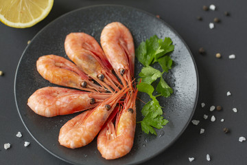 Cooked shrimps on plate with lemon, salt, pepper. Seafood appetizer.