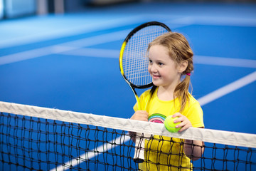 Child playing tennis on indoor court